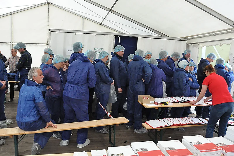Lange Schlange von Menschen in blauen Overalls Lange Schlange von Menschen in blauen Overalls