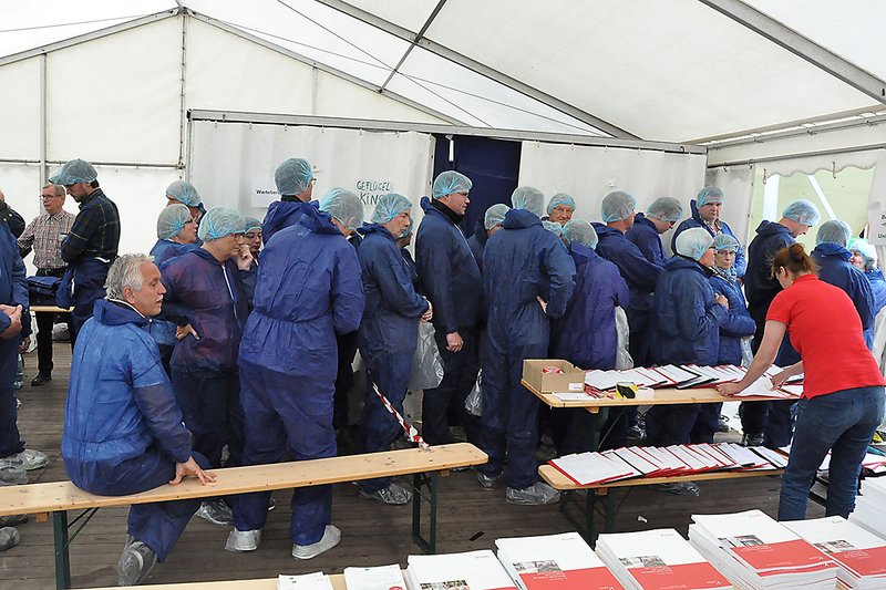 Lange Schlange von Menschen in blauen Overalls