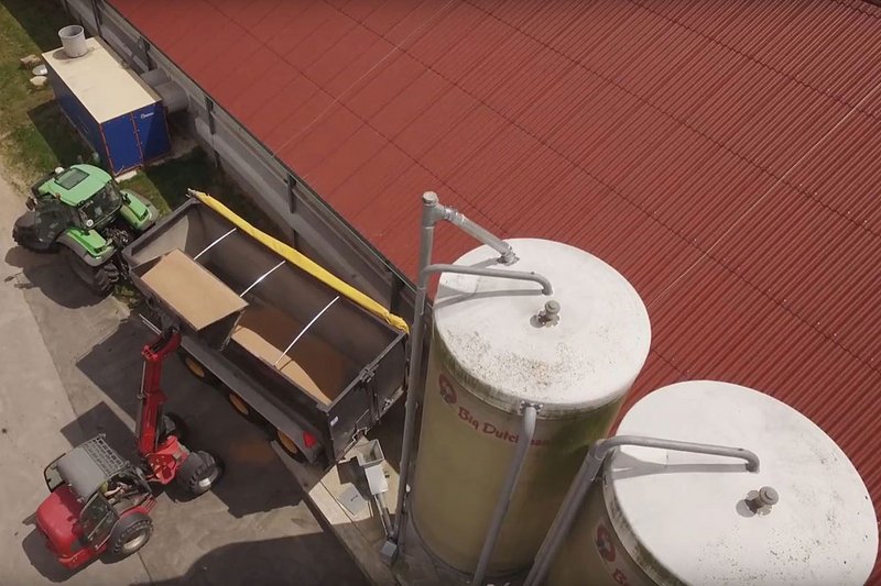 Luftaufnahme von Stall, Silos und Wärmetauscher. Außerdem wird Weizen verladen. 