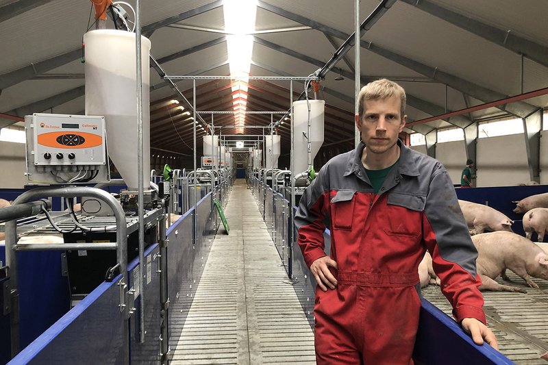 L’agriculteur se tient dans un long couloir contenant des cases à gauche et à droite