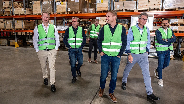 Ulf Meyer (links) und Kollegen bei der Besichtigung des Logistikzentrums in Bakum – ein Highlight des Treffens. Mehrere Personen gehen durch das Lager
