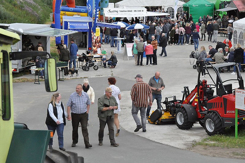 Besucher umgeben von Landmaschinen, Hüpfburg und anderen Ständen