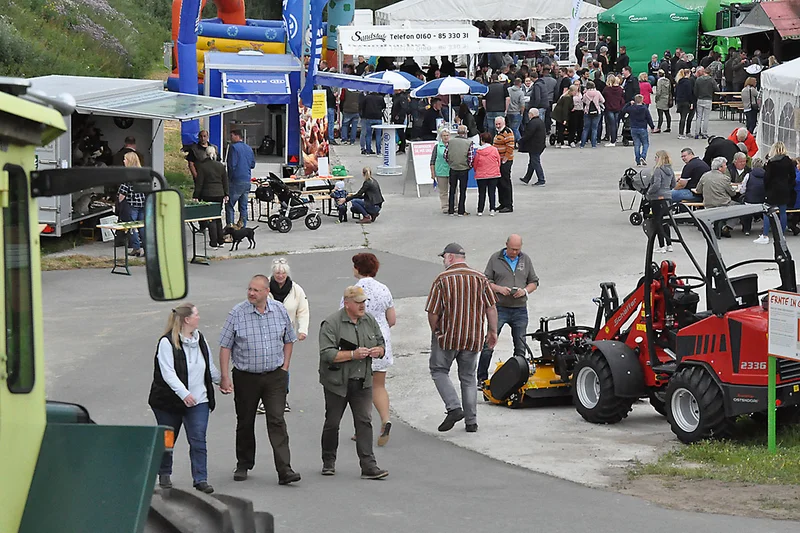Besucher umgeben von Landmaschinen, Hüpfburg und anderen Ständen Besucher umgeben von Landmaschinen, Hüpfburg und anderen Ständen